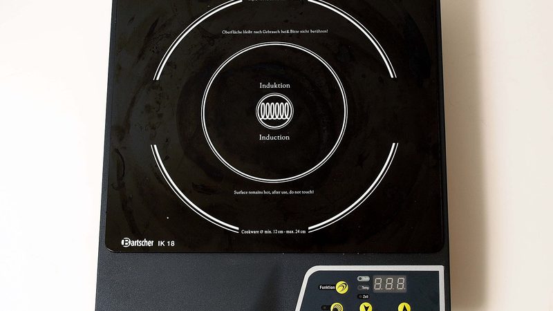 A white induction cooktop on a kitchen counter, a mains appliance