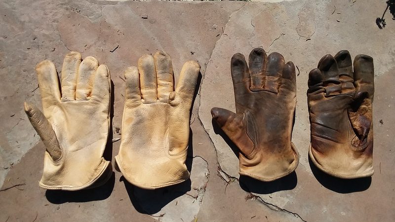 A worn pair of leather work gloves